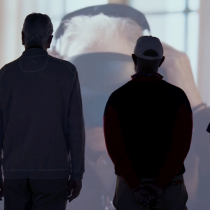 Silhouettes of four people watching a film on a large screen 