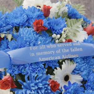 A flower bouquet with ribbon that reads "For all who served and In memory of the fallen American Airlines"