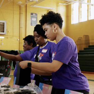 Girls wearing FedEx shirts at a table inside a gym