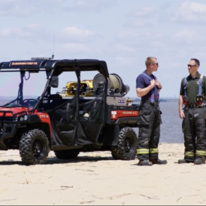 The Fire Department's utility terrain vehicle parked on a beach with two men standing nearby