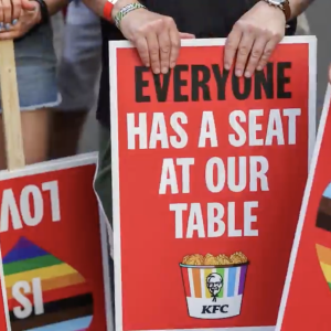 People holding signs that read "everyone has a seat at our table"