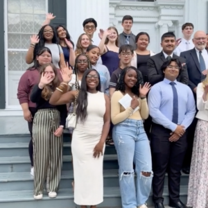 Group of students standing on steps, waving