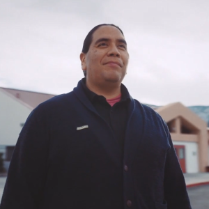 A smiling person outside a school building
