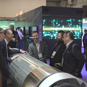 People talking over a large metal cylinder at a convention.