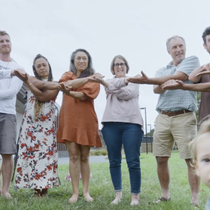 A group of people with interconnected arms standing outside