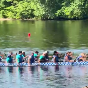 A team rowing in a dragon boat on a body of water.