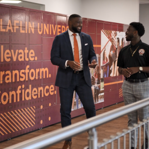 The Dean and a student smiling and talking as they walk through a hall way at the school.
