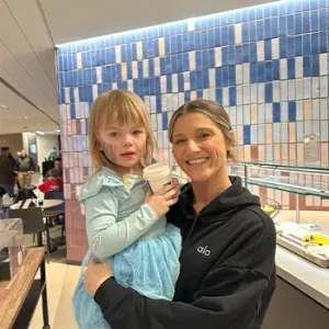 Britney Ruby Miller holding a child in a cafeteria setting.