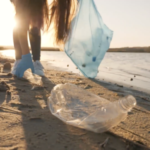 A person picking up plastic waste on a beach