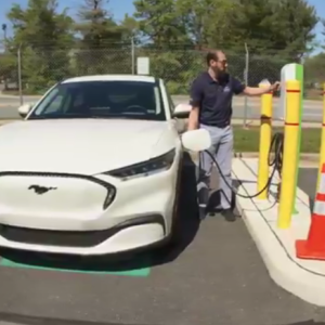 A person next to a vehicle and charging station