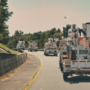 Four line-worker bucket-trucks driving down a road.