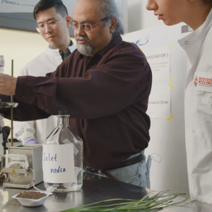 A teacher and two students working on an experiment