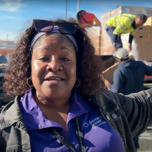 An employee speaks and gestures to people loading boxes on a truck