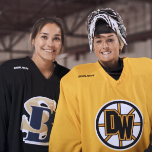 Two Alumni in hockey uniforms posed together on an ice rink.