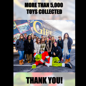 A group posed in front of a semi truck. A person dressed as the Grinch laid out in front of them. "Over 5000 toys collected, Thank you!"