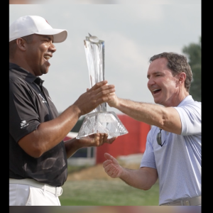 Two people celebrating, one holding a trophy.