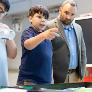 Greg Pardo looks over two students