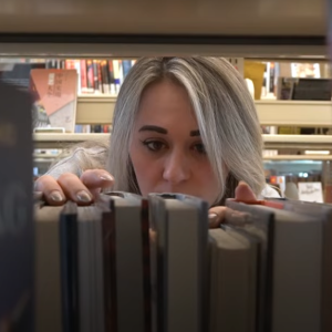 Someone looking through a bookshelf