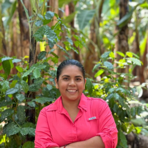 Ana, a banana farmer in Ecuador, stands near banana plants and explains how they grow in generations. 
