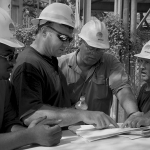 4 people in hardhats looking at papers