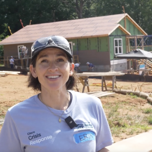 Person speaking in front of house being rebuilt