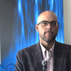 Man wearing glasses in front of backdrop
