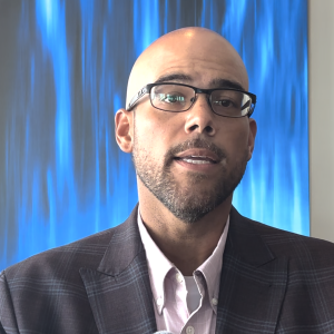 Man wearing glasses in front of backdrop