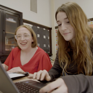 Educator and student working on a laptop