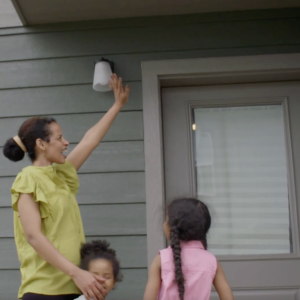 Family standing by front door waving at camera