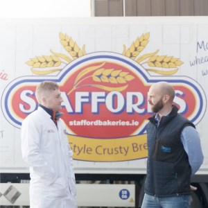 Two people speaking in front of Stafford Bakery truck