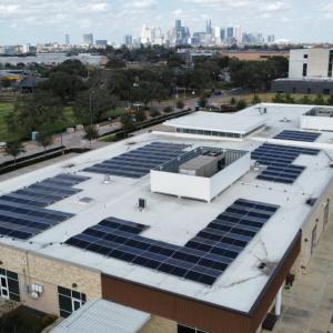 Solar panels on a roof with the Houston skyline in the background