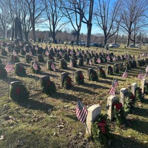 Wreaths placed on headstones with American flags