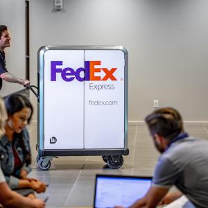 Person in a FedEx uniform pushing an electric pallet