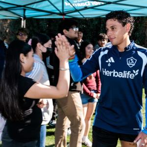 LA Galaxy player Edwin Cerillo greets a student during a meet‑and‑greet at a preseason training session, creating personal connections through sport and mentorship.