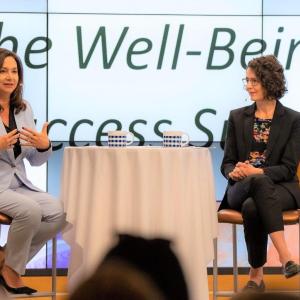 Two people sat on chairs talking on a stage at the Well-Being and Success Summit