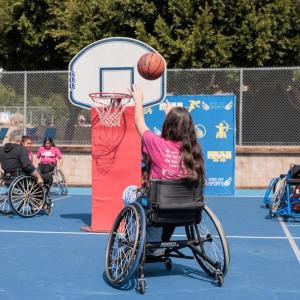 A girl in a sports wheelchair shoots a basketball during an adaptive sports activity at Girls Empowerment Day.