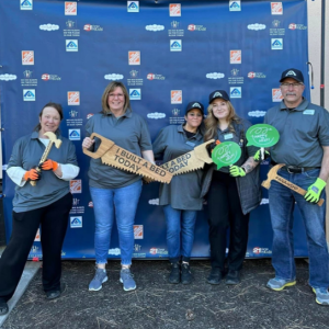 People posing with prop saws that read "I BUILT A BED TODAY"