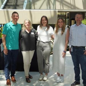 Five people posing for picture in office