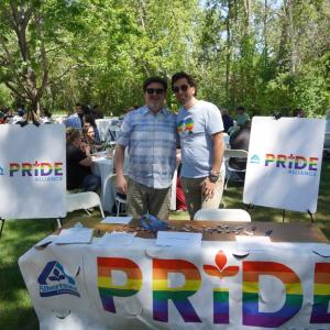 Two people posing at booth that says "PRIDE"
