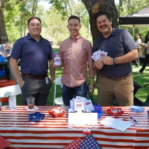 Three people posing at booth with American flags