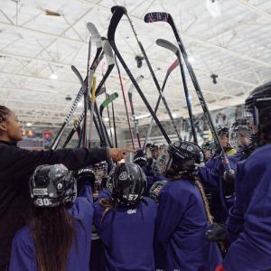 Players huddle on ice with their hockey sticks raised