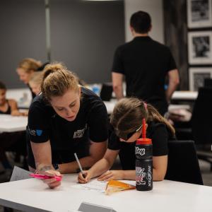 LA Kings Girls Camp participant completes a worksheet while working alongside a coach during an educational session