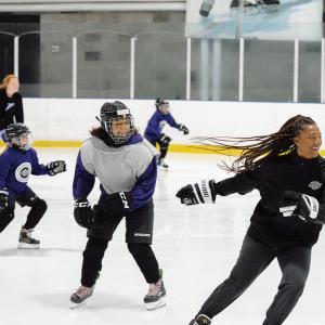 Coach Blake Bolden skates with participant during camp