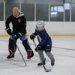 Participant receives one-on-one guidance with Kings broadcaster and alumnus Daryl Evans during an on-ice hockey skills session