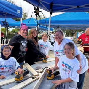Group of people sanding wood planks