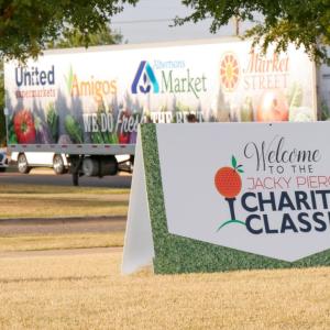 Sign with text "Welcome to the Jacky Pierce Charity Classic" in front of an Albertsons Market trailer