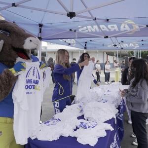 Los Angeles Rams' mascot and others holding t-shirts that read "WE ARE FOOTBALL"