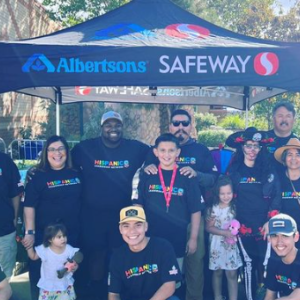 Group of people pose in front of Albertsons' tent for picture at Annual Chile & Frijoles Festival