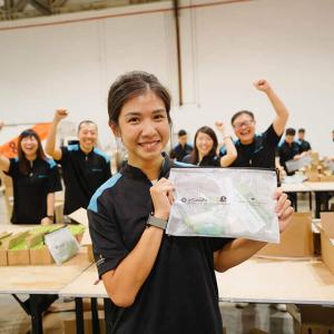Someone holding up a hygiene kit, with cheering people in the background