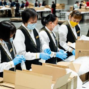People in masks and gloves working with boxes on tables